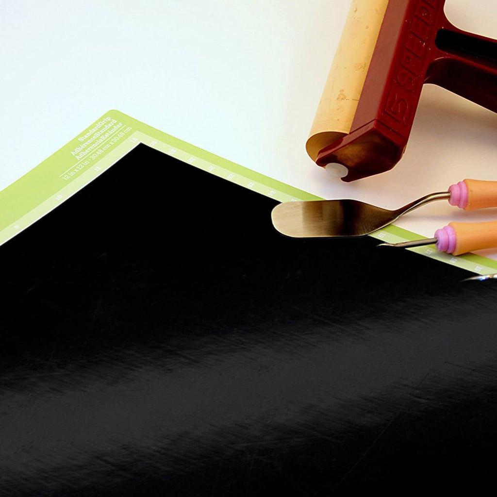 Glossy Black permanent vinyl sheet on cutting board with weeding tools  beside it. 